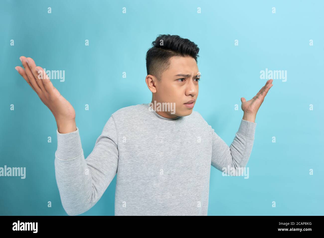 Vista laterale di un uomo arrabbiato gridando e gesturando con le mani isolate su sfondo blu Foto Stock