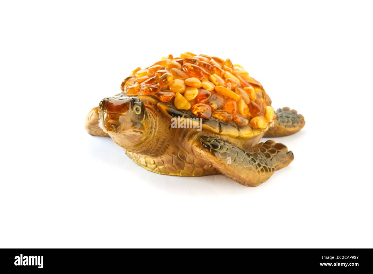 Figura di una tartaruga su sfondo bianco con pietre ambra sulla conchiglia. Vista frontale. Foto Stock