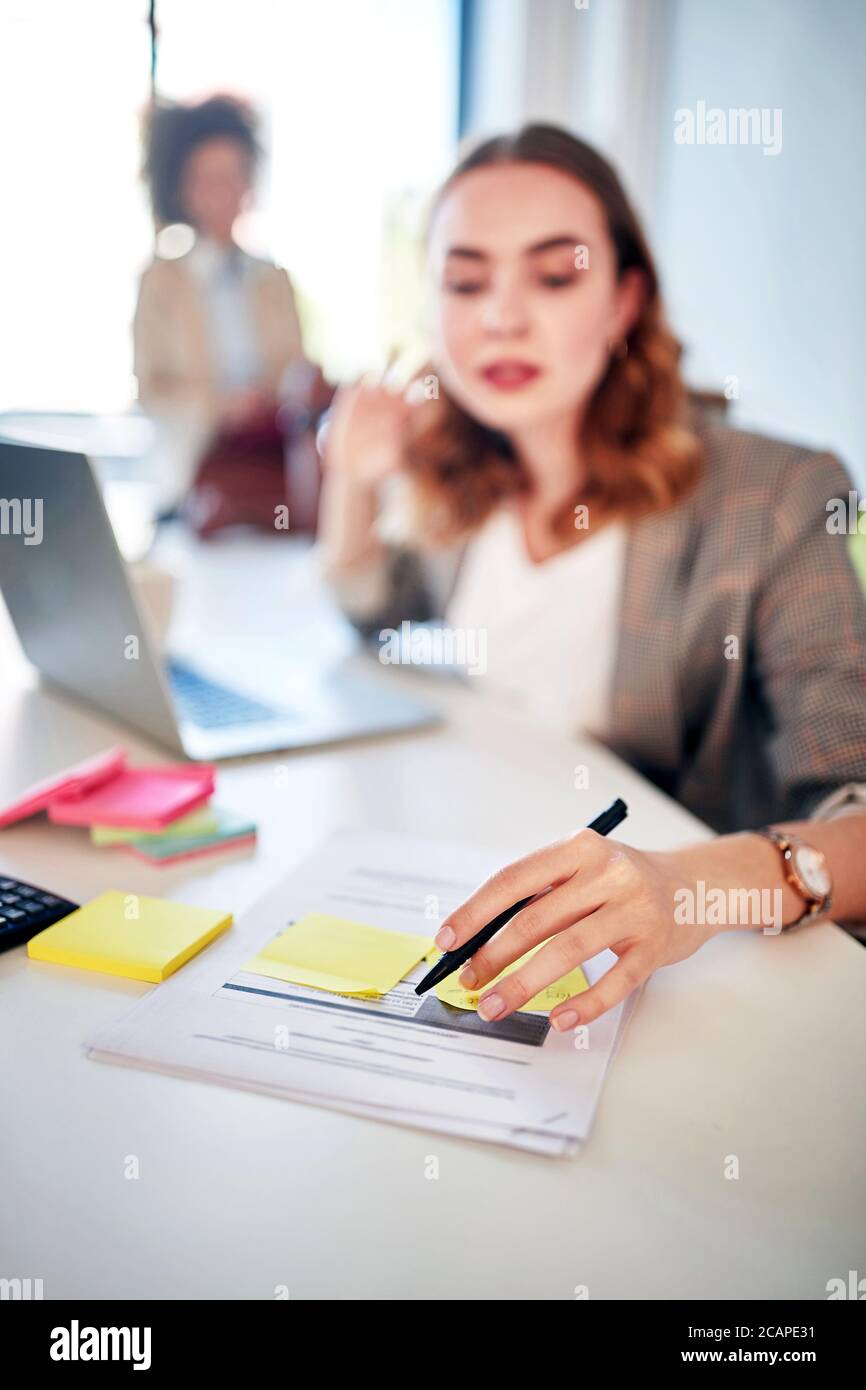 Giovane donna che lavora in ufficio scrivendo su una carta Foto Stock