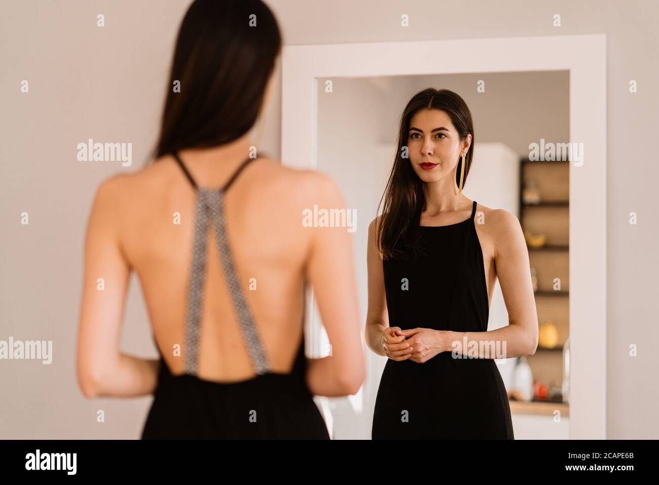 Donna in un lungo vestito nero con schiena nuda guardando il suo