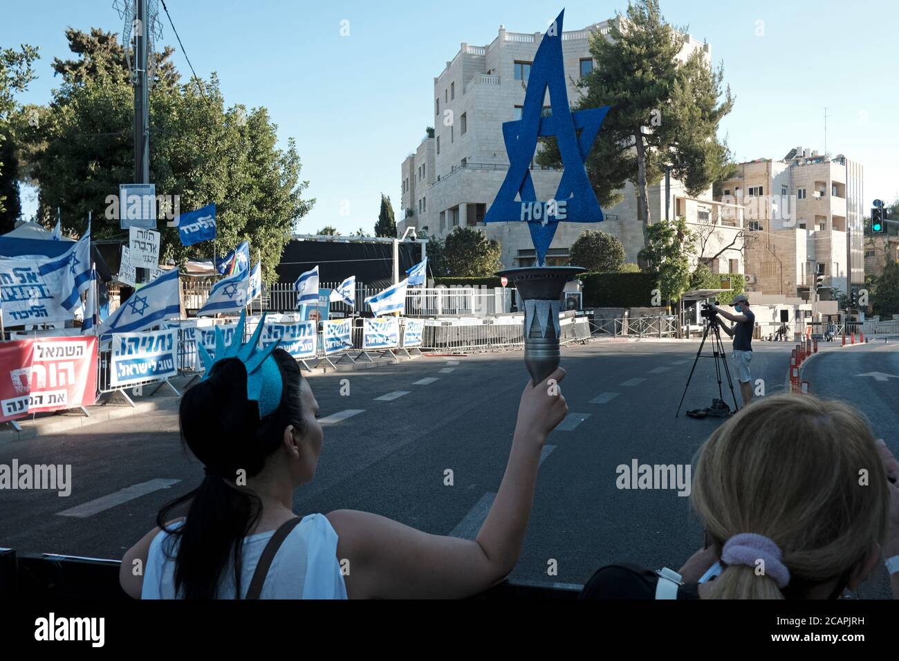 Il dimostratore tiene una torcia a forma della stella ebraica di Davide mentre circa 3,000 persone hanno protestato contro il primo ministro Benjamin Netanyahu fuori dalla sua residenza ufficiale a Gerusalemme venerdì sera, l'ultima di una serie di manifestazioni che lo hanno chiesto di uscire il 07 agosto 2020 a Gerusalemme, Israele. Gli israeliani sono scesi in piazza con manifestazioni quasi quotidiane che hanno chiesto a Netanyahu di rassegnarsi sulle sue accuse di corruzione e su ciò che chiamano cattiva gestione della crisi del coronavirus e assalto alla democrazia. Foto Stock