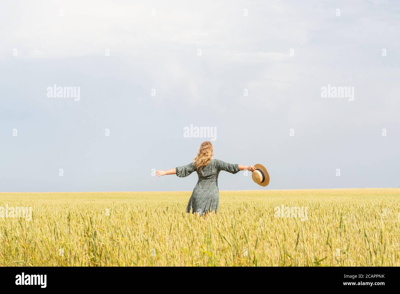 Donna in cappello di paglia che cammina attraverso il campo di segale sopra giorno d'estate Foto Stock