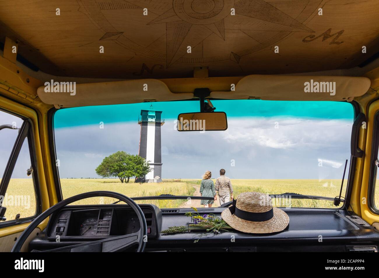 Giovane coppia dell'Europa orientale che viaggia in un camper giallo attraverso la campagna. Campeggio off-grid auto-costruito in campeggio nella natura selvaggia. Foto Stock