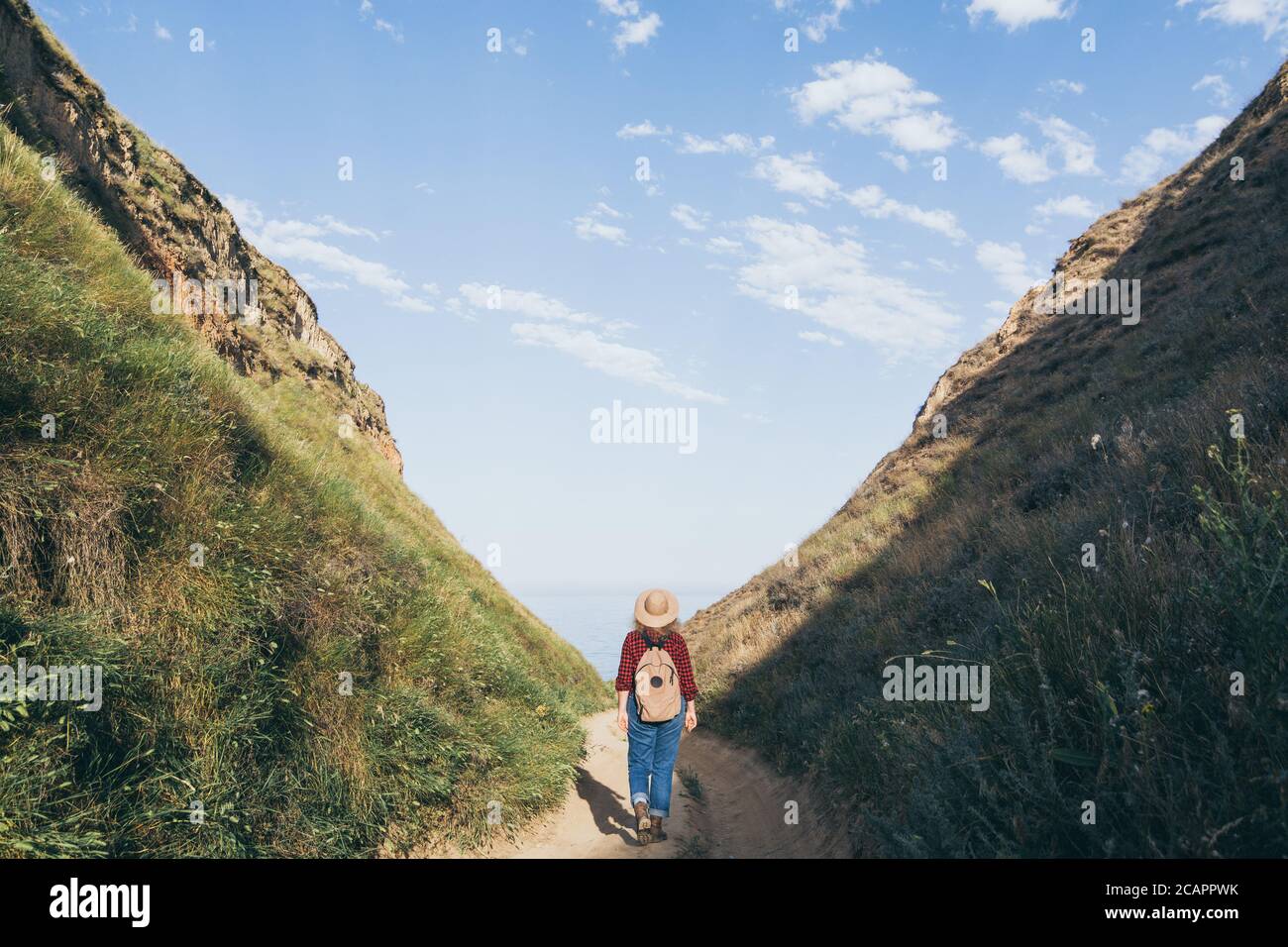 Donna con zaino escursionismo nel canyon di montagna con vista sul mare Foto Stock
