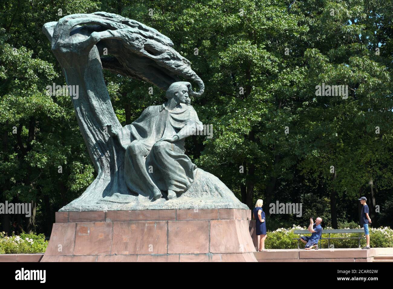 Varsavia Polonia una famiglia posta in posa dalla statua del compositore polacco Frederyk Chopin nei giardini del Parco Lazienki nell'estate 2020 Foto Stock