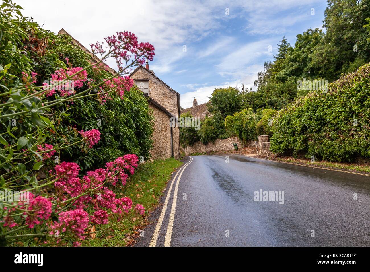 Una strada arenata che conduce tra case a nido d'ape nella campagna Engish di Cotswolds, Regno Unito Foto Stock