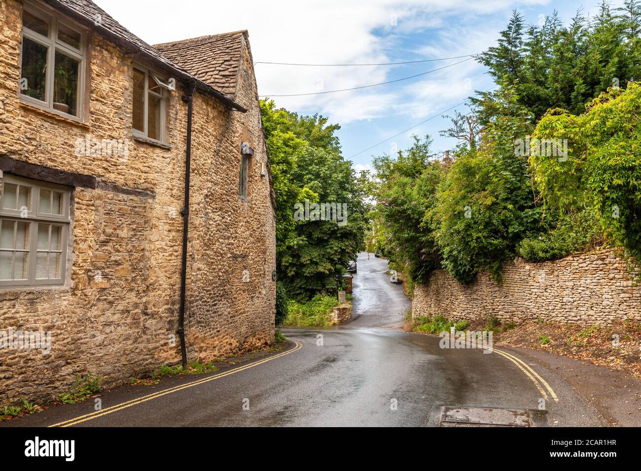 Una strada tra i famosi cottage a nido d'ape nel villaggio di campagna di Castle Combe a Cotswolds, Regno Unito Foto Stock