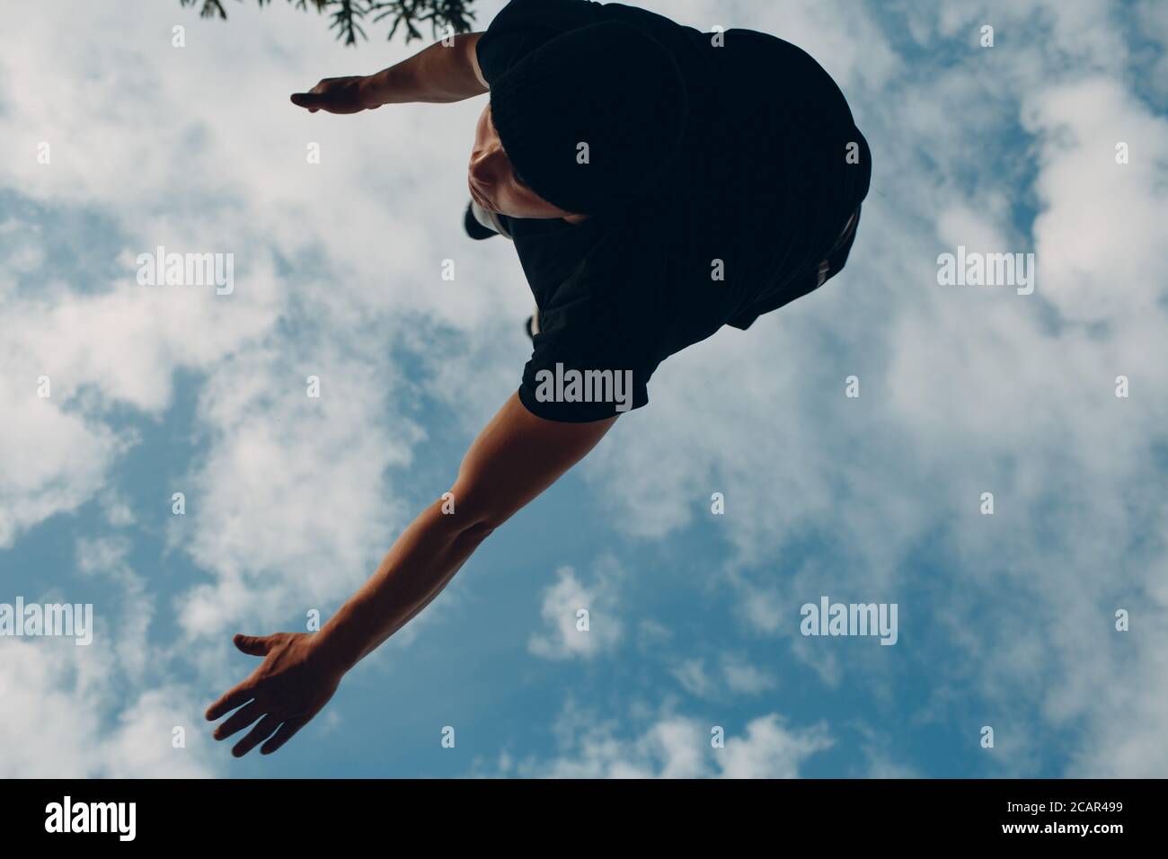 Giovane uomo sportivo salta parkour. Vista dal basso. Foto Stock
