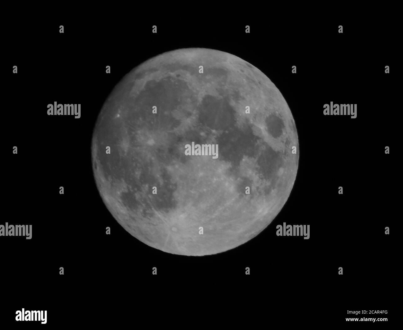 Teleobiettivo estremo in bianco e nero della luna piena contro un cielo completamente nero Foto Stock