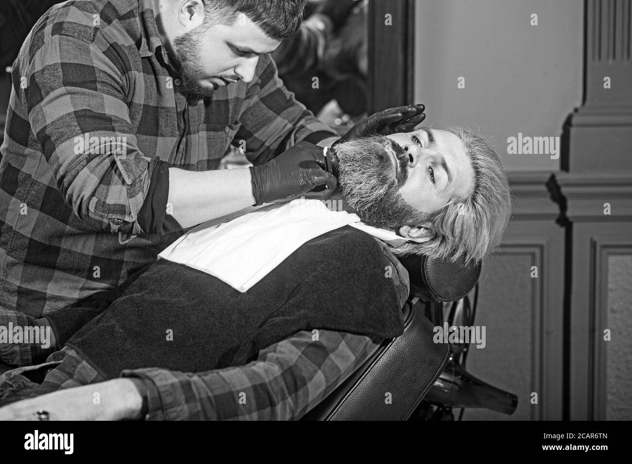 Uomo hipster seduto in poltrona barbiere. Foto Stock