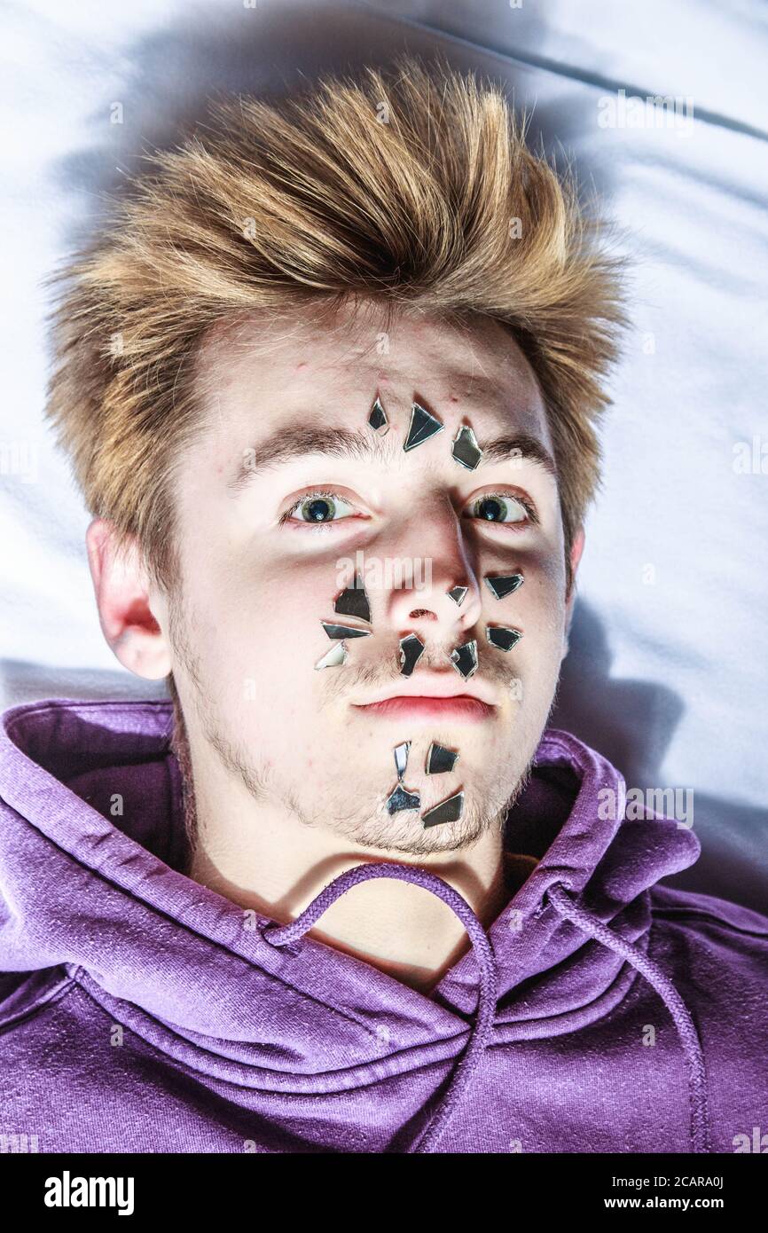 Ragazzo con pezzi di specchio rotto sulla faccia Foto Stock