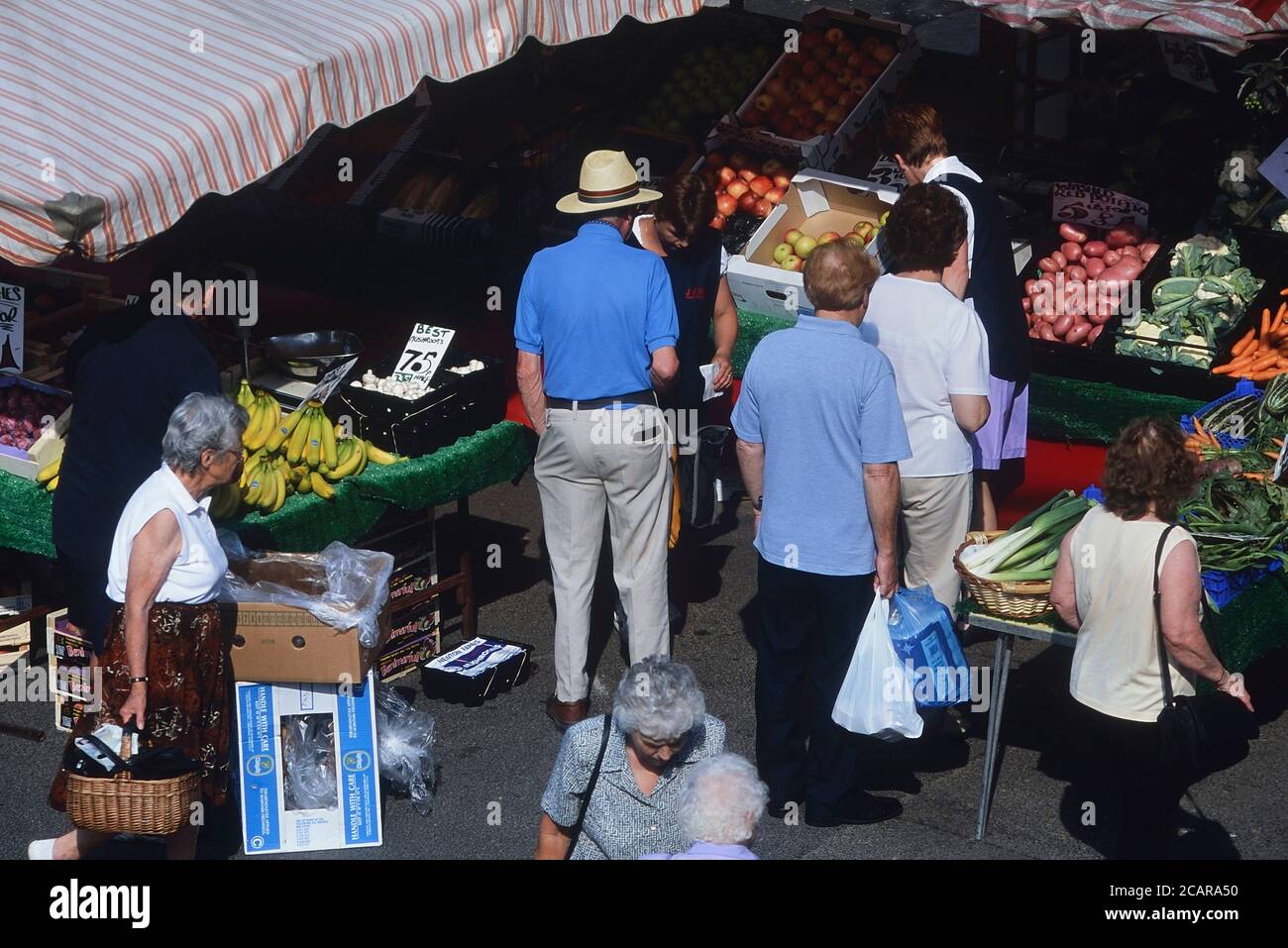 I clienti si accodano in una bancarella di frutta e verdura. Mercato di Horncastle, Lincolnshire, Inghilterra, Regno Unito Foto Stock