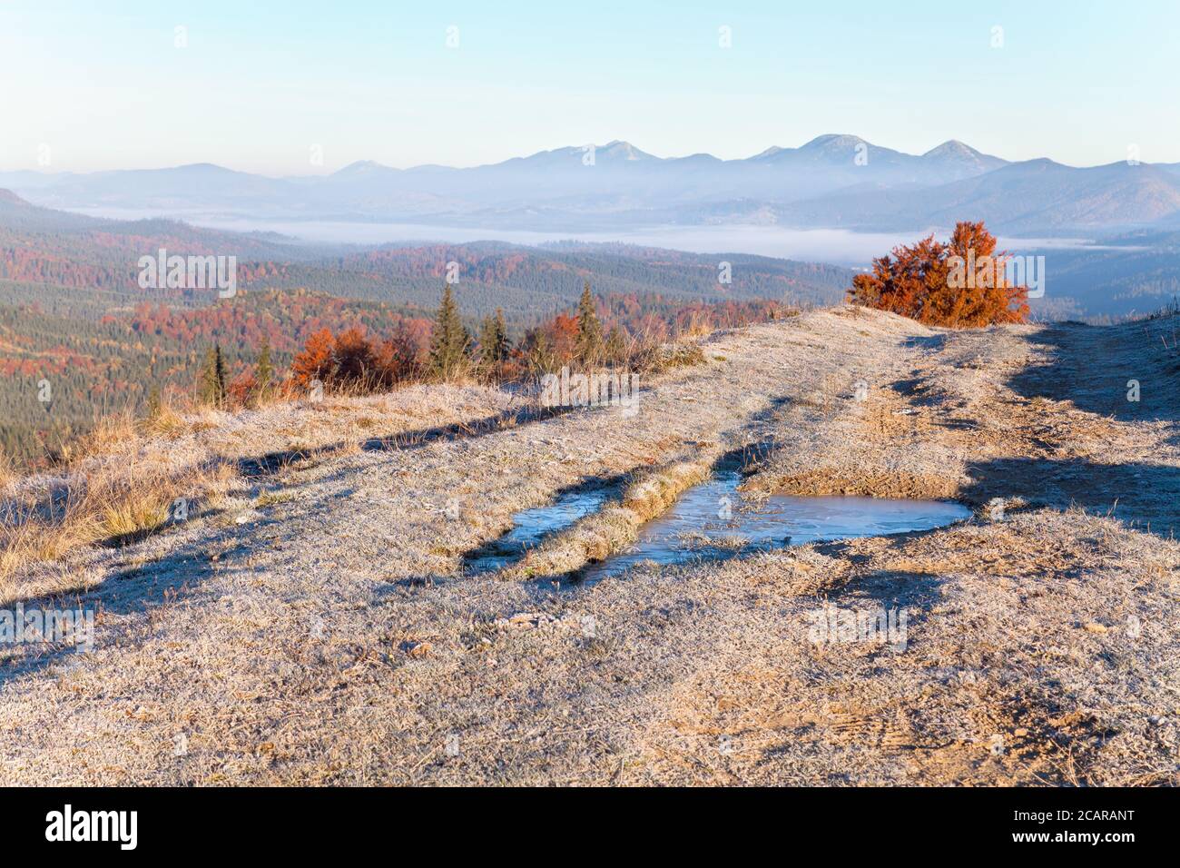 Mattina d'autunno gelida sul passo di montagna, luminosi versanti di montagna, lontane montagne nella nebbia. Foto Stock