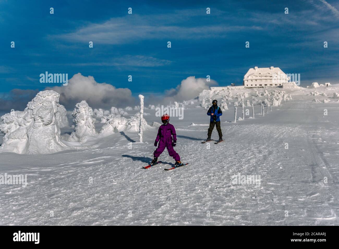 Sciare uomo e bambino in forte vento d'inverno vicino al rifugio alla cima di Szrenica, Parco Nazionale di Karkonosze, al confine tra Polonia e Repubblica Ceca Foto Stock