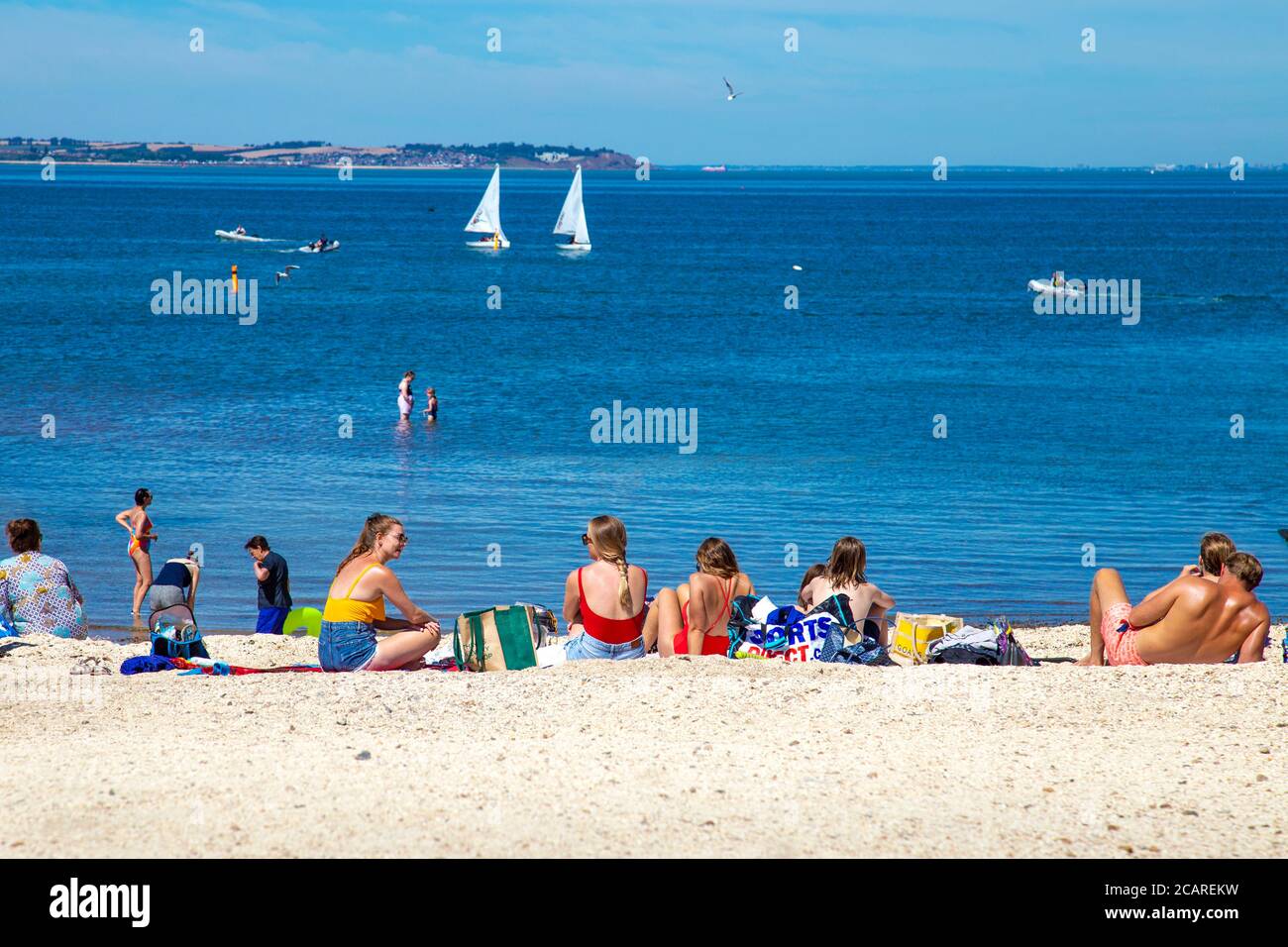 La gente prende il sole e si gode l'onda di calore alla Whitstable Beach, Kent, Regno Unito Foto Stock