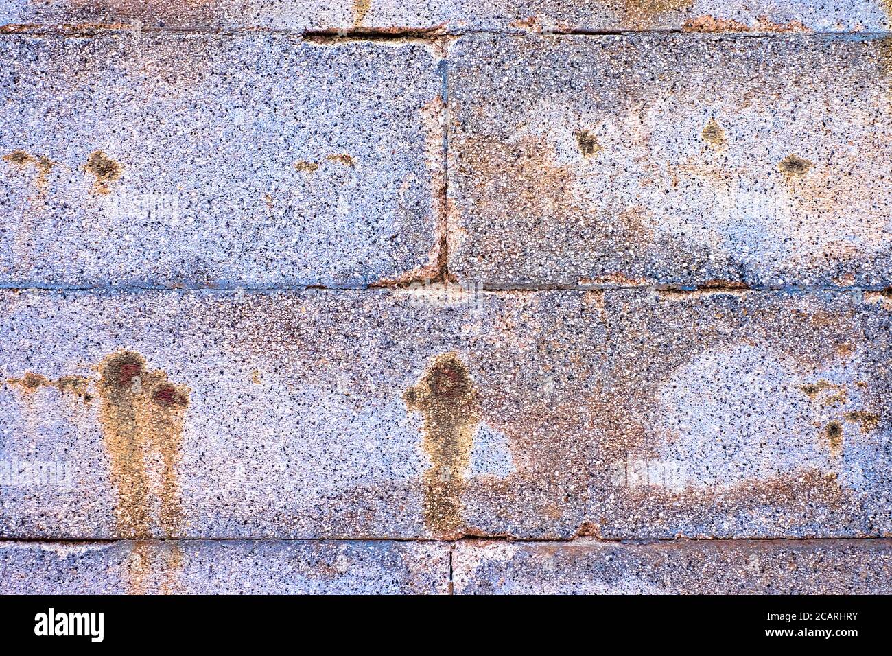 Blocchi di pietra colorati invecchiati, parete grigio argento con macchie arrugginite. Foto Stock