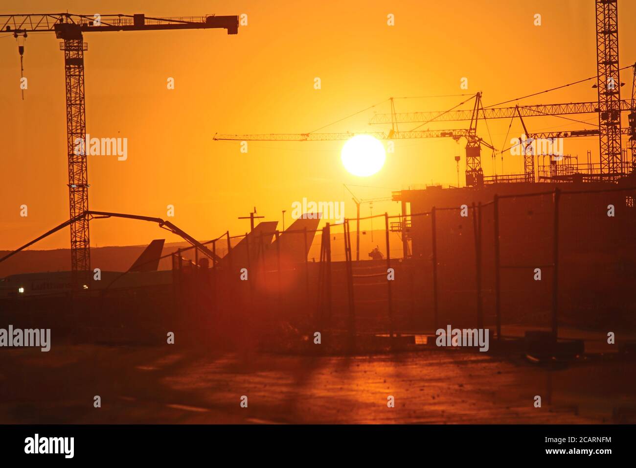 Aerei e gru all'aeroporto di Francoforte durante il tramonto Foto Stock