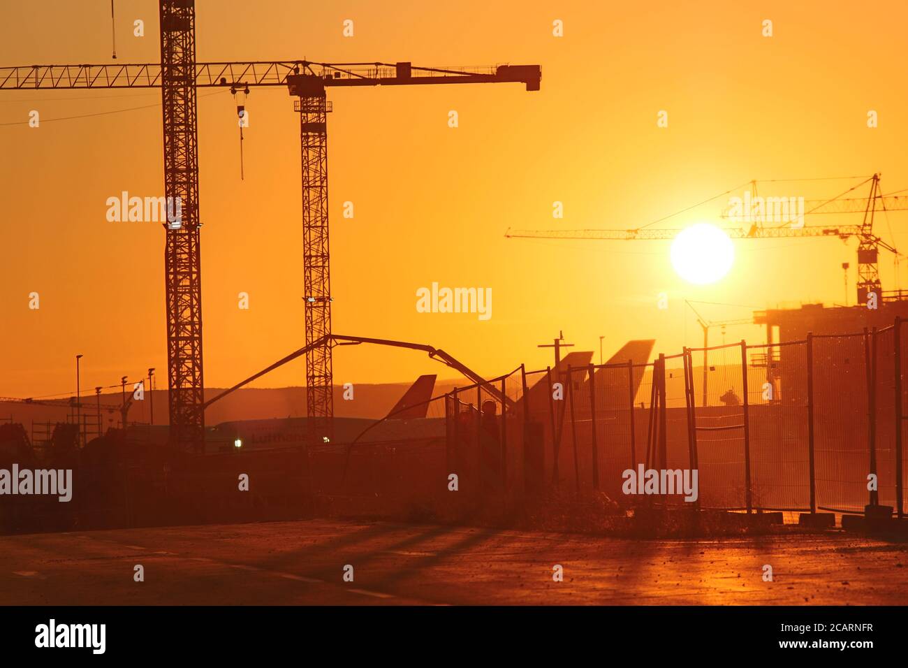 Aerei e gru all'aeroporto di Francoforte durante il tramonto Foto Stock