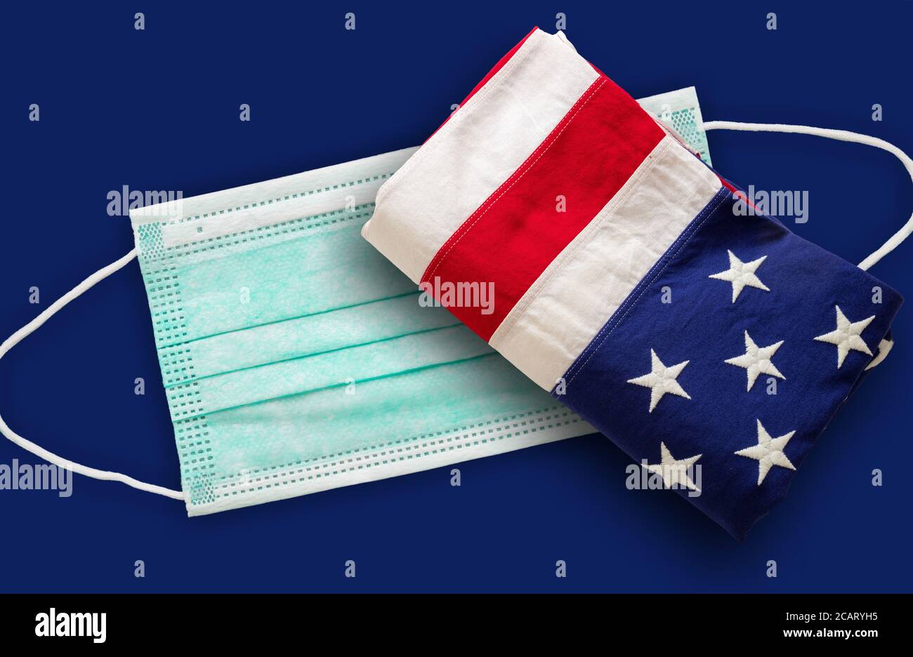 Coronavirus Covid 19 negli Stati Uniti. Maschera medica protettiva e bandiera degli Stati Uniti d'America contro sfondo bleu. Foto Stock