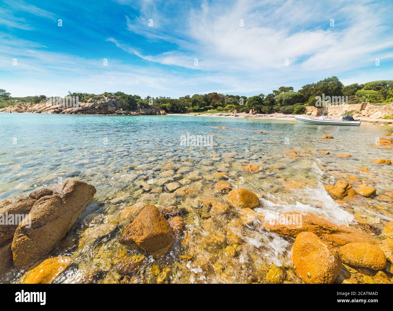 Rocce gialle e gommone in una piccola insenatura in Sardegna, Italia Foto Stock