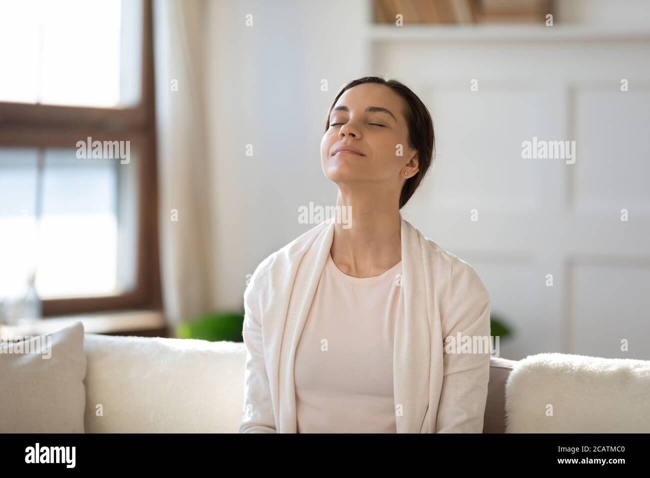 Giovane donna attenta che respira aria fresca con gli occhi chiusi. Foto Stock