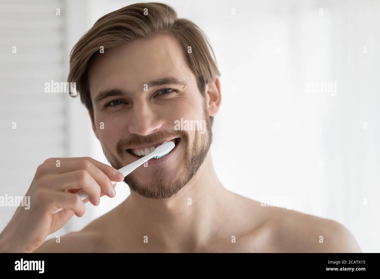 Ritratto della testa sorridente giovane uomo spazzolando i denti, igiene orale Foto Stock
