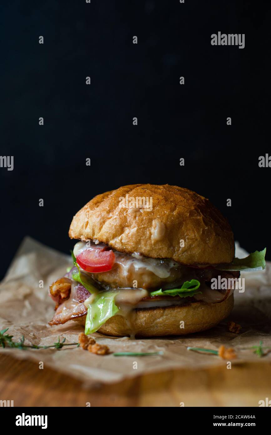 hamburger fresco e gustoso su sfondo nero. Delizioso hamburger fatto in casa su un tavolo di legno Foto Stock