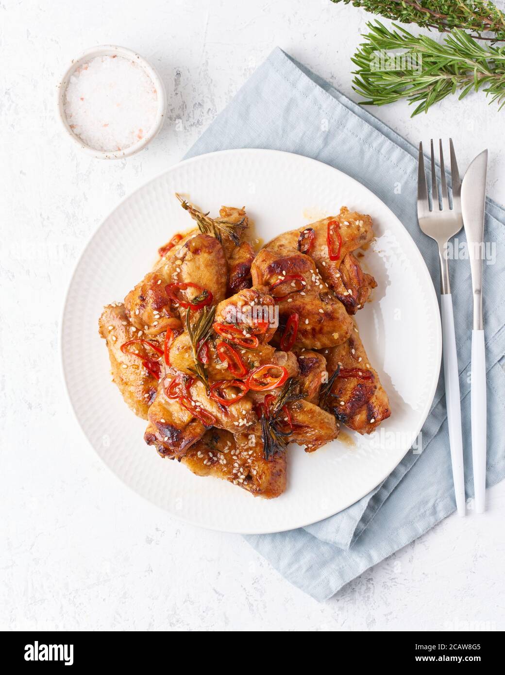 Ali di pollo alla griglia. Scalpello cotto al forno su piatto in salsa rossa. Piatti asiatici caldi. Vista dall'alto, verticale Foto Stock