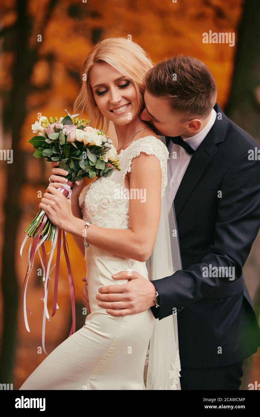 Lo sposo bacia la sposa. Donna elegante e bella con bouquet di fiori. Lo  sposo in un vestito nero. Felice e giovane coppia sposata. Matrimonio  d'autunno Foto stock - Alamy