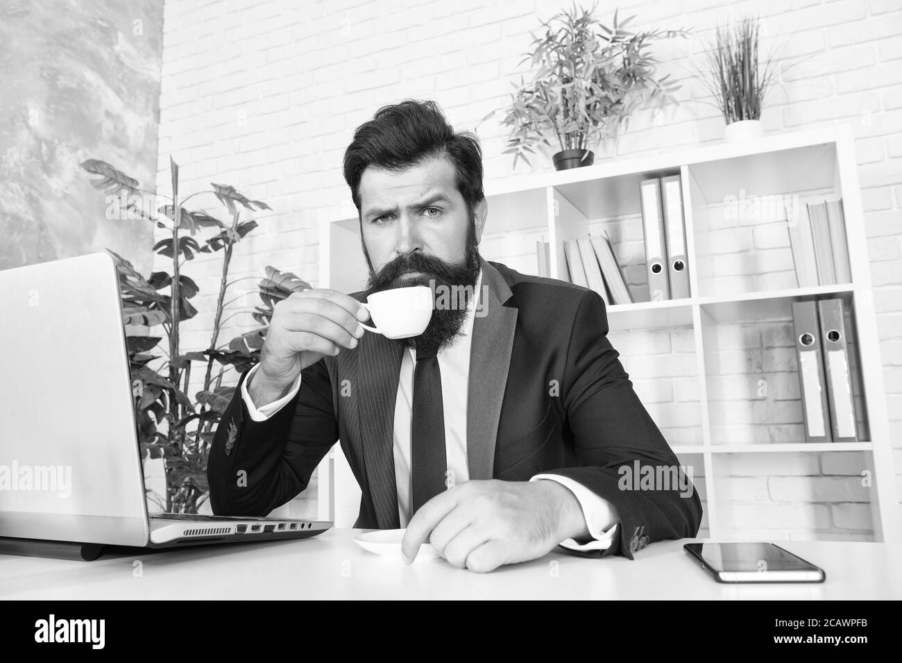 Spazio di lavoro confortevole. Abito formale con bearded hipster rilassante con caffè. La vita di ufficio è impensabile senza buon caffè. Sala ricevimento. rispettabile ceo. Uomo bel boss sedersi in ufficio bere caffè. Foto Stock