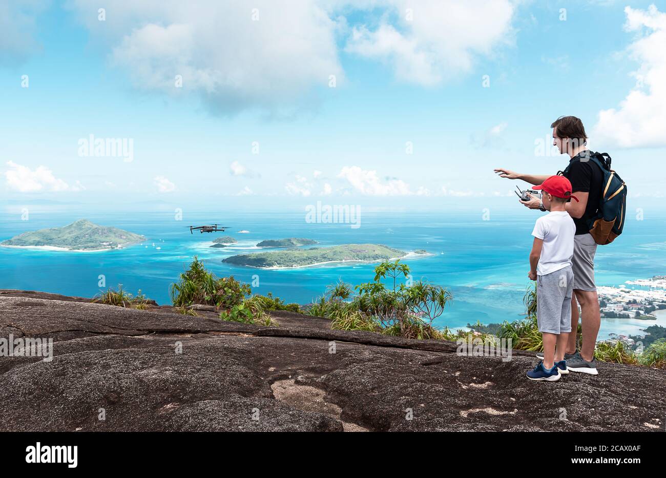Fratelli con grande differenza di età in piedi su una parte superiore di montagna con vista mozzafiato sull'isola delle Seychelles Foto Stock