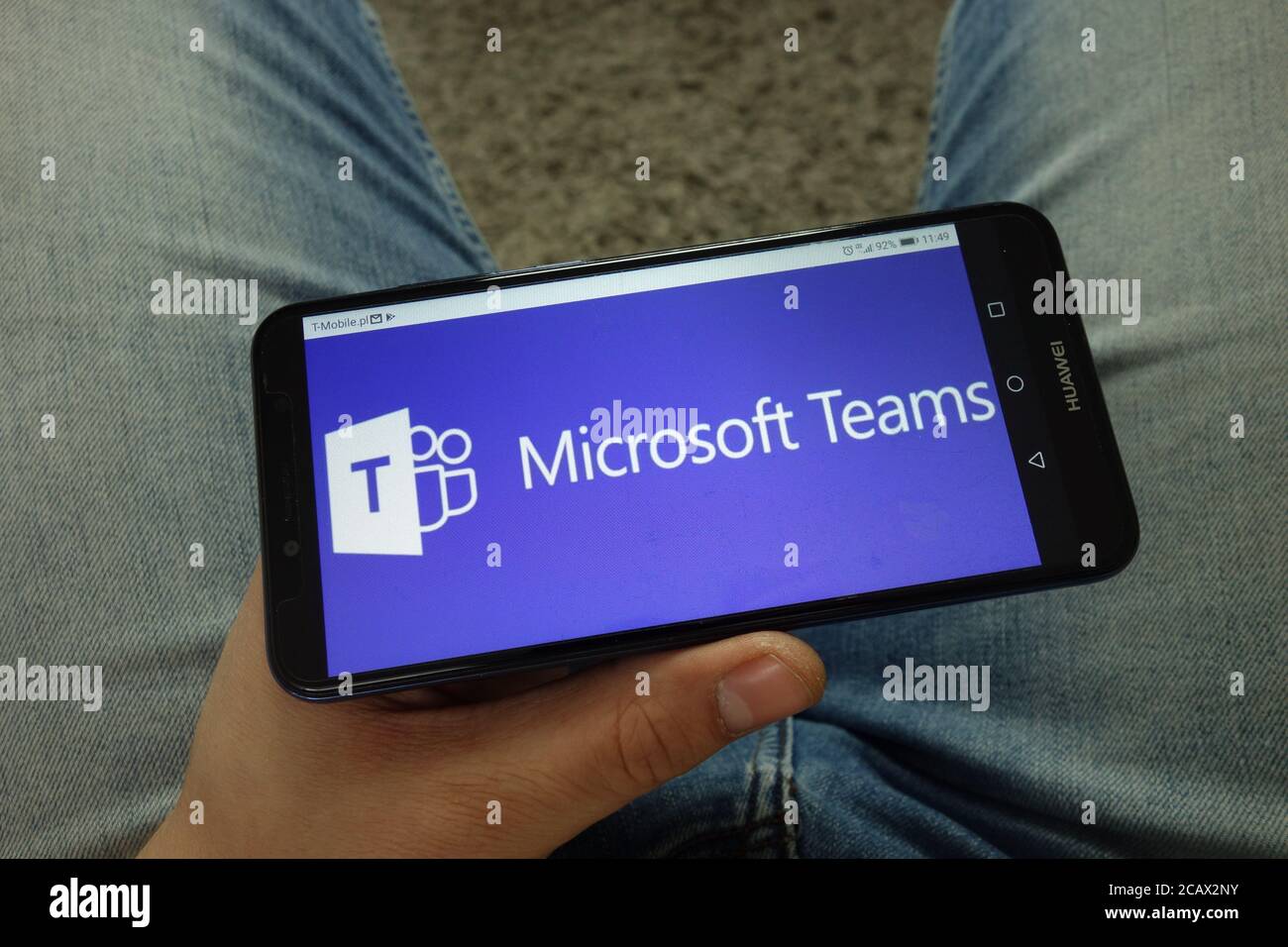 Uomo che tiene uno smartphone con il logo della piattaforma di comunicazione Microsoft Teams Foto Stock