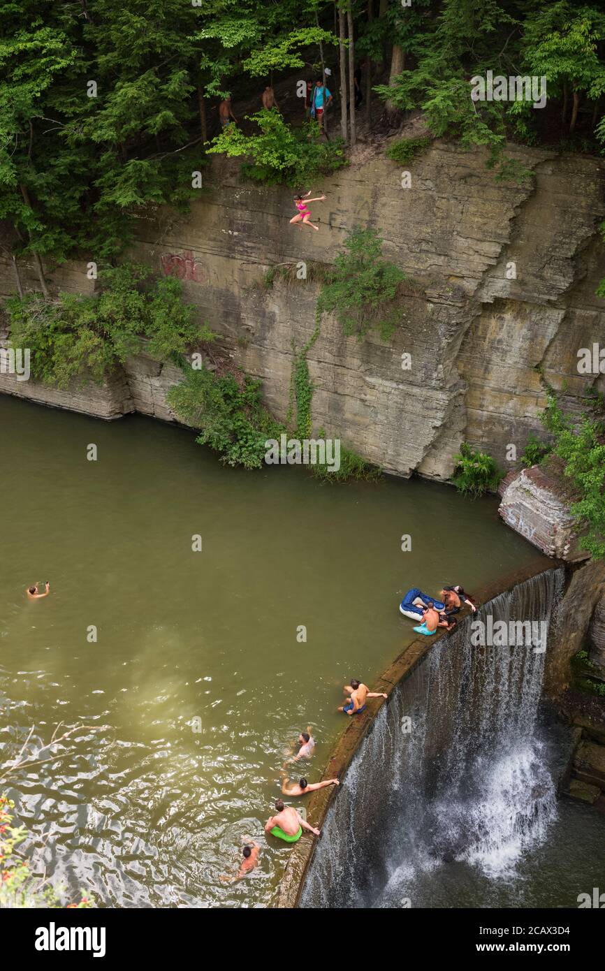 Ithaca, NY/USA-2 agosto 2020: Una giovane donna salta da una scogliera in una piscina naturale di acqua a Six-Mile Creek. Molti si affollano a livello locale, statale e federale Foto Stock