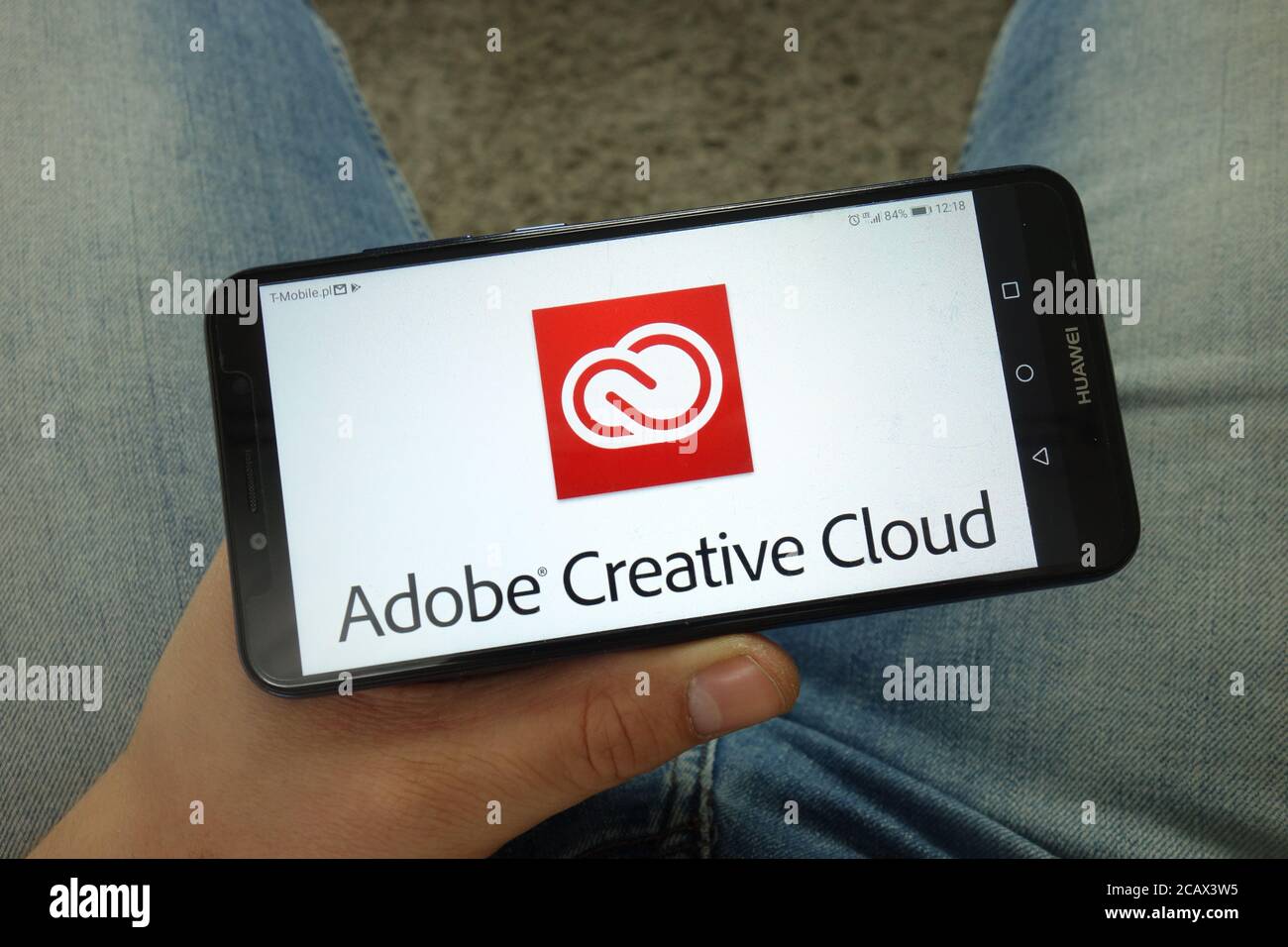 Uomo che tiene uno smartphone con il logo Adobe Creative Cloud Foto Stock