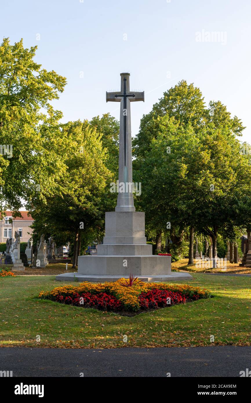 Una croce di pietra circondata da fiori come parte di un memoriale di guerra in un cimitero Foto Stock