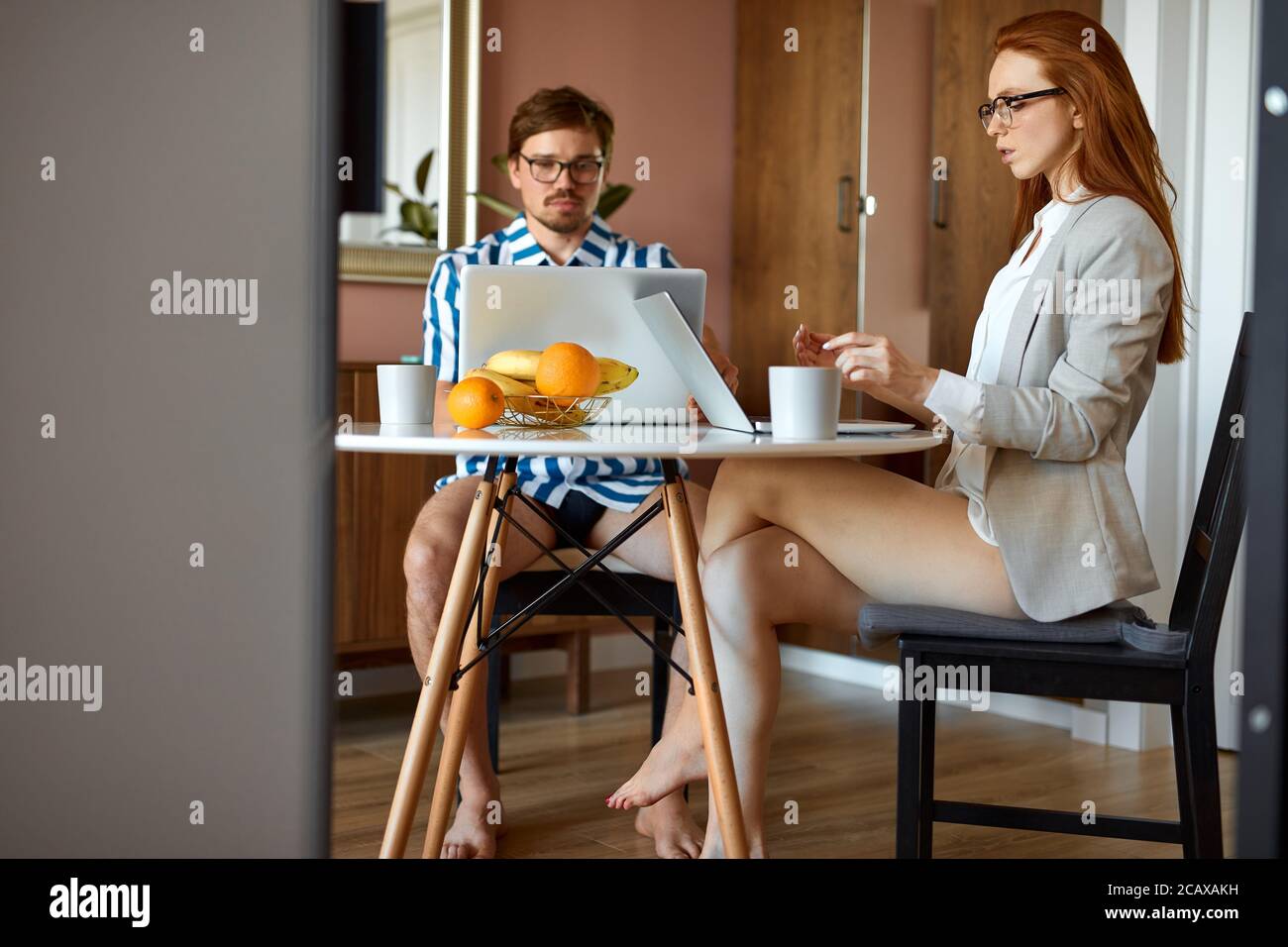 coppie sposate lavorano su computer portatile a casa, si siedono in cucina insieme, entrambi su freelance Foto Stock