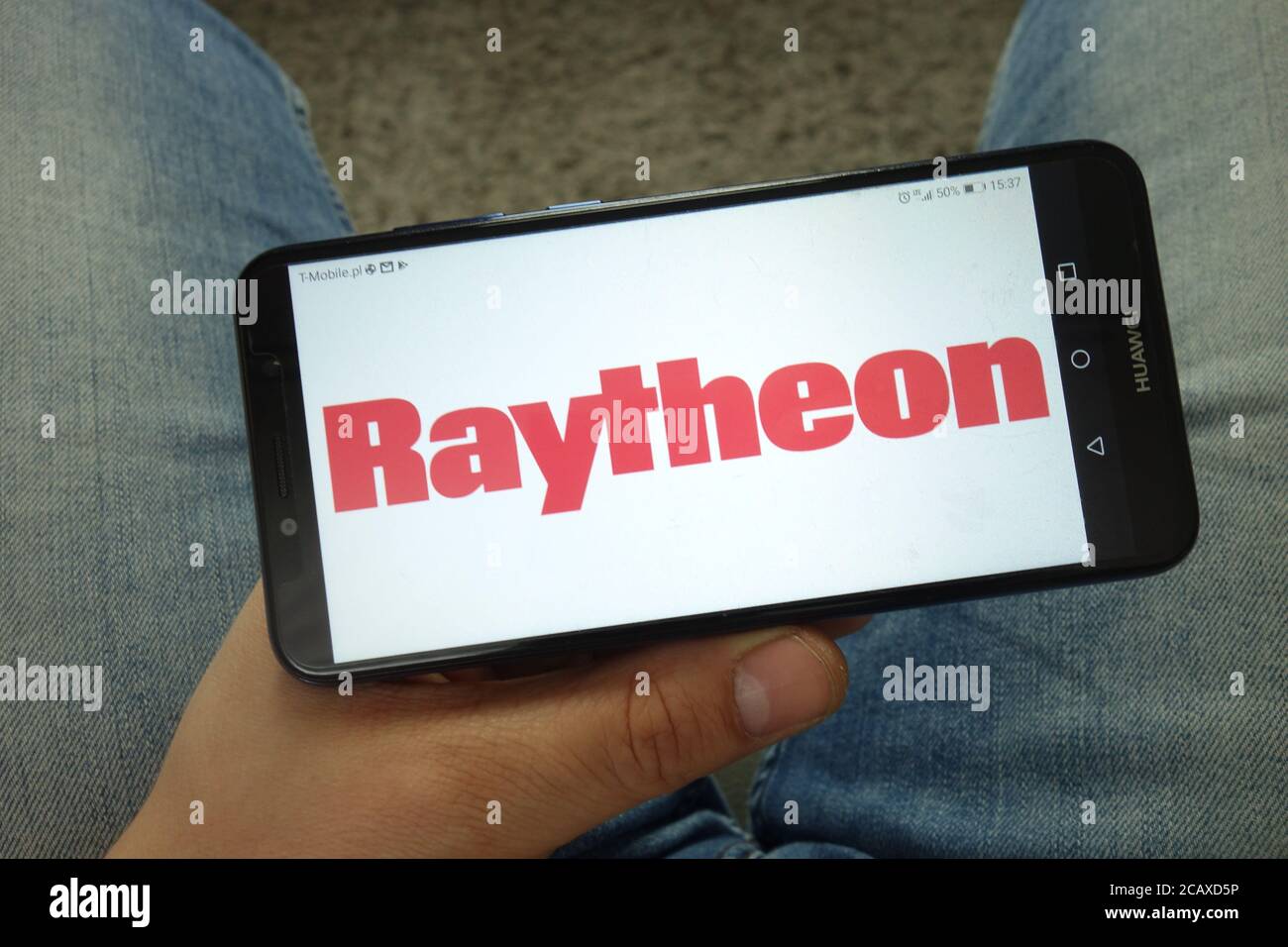 Uomo che tiene lo smartphone con il logo Raytheon Company Foto Stock