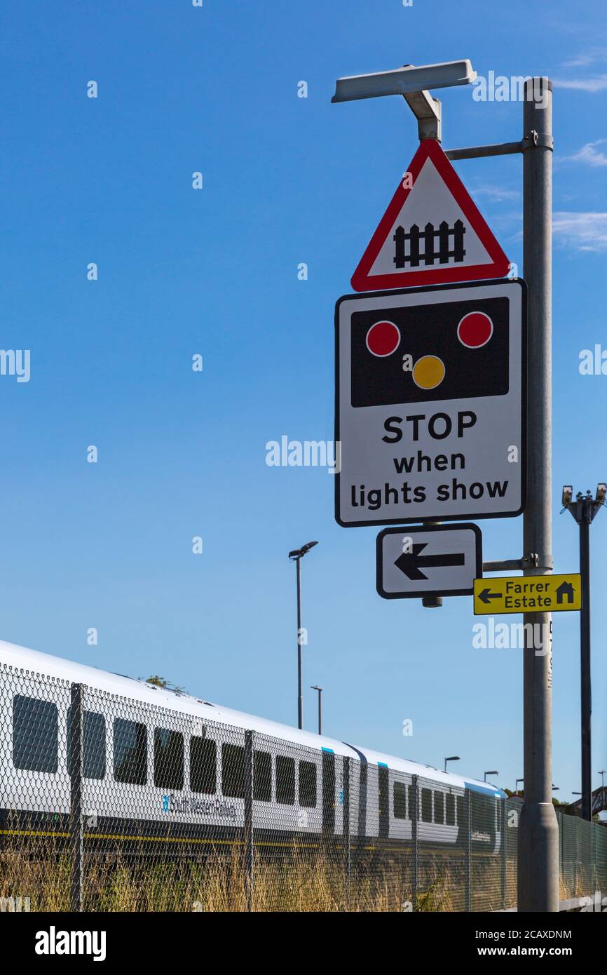 Treno ferroviario Sud Ovest che si avvicina alla stazione ferroviaria di Wool con fermata quando le luci mostrano il cartello per l'attraversamento del livello a Wool, Dorset UK nel mese di agosto Foto Stock