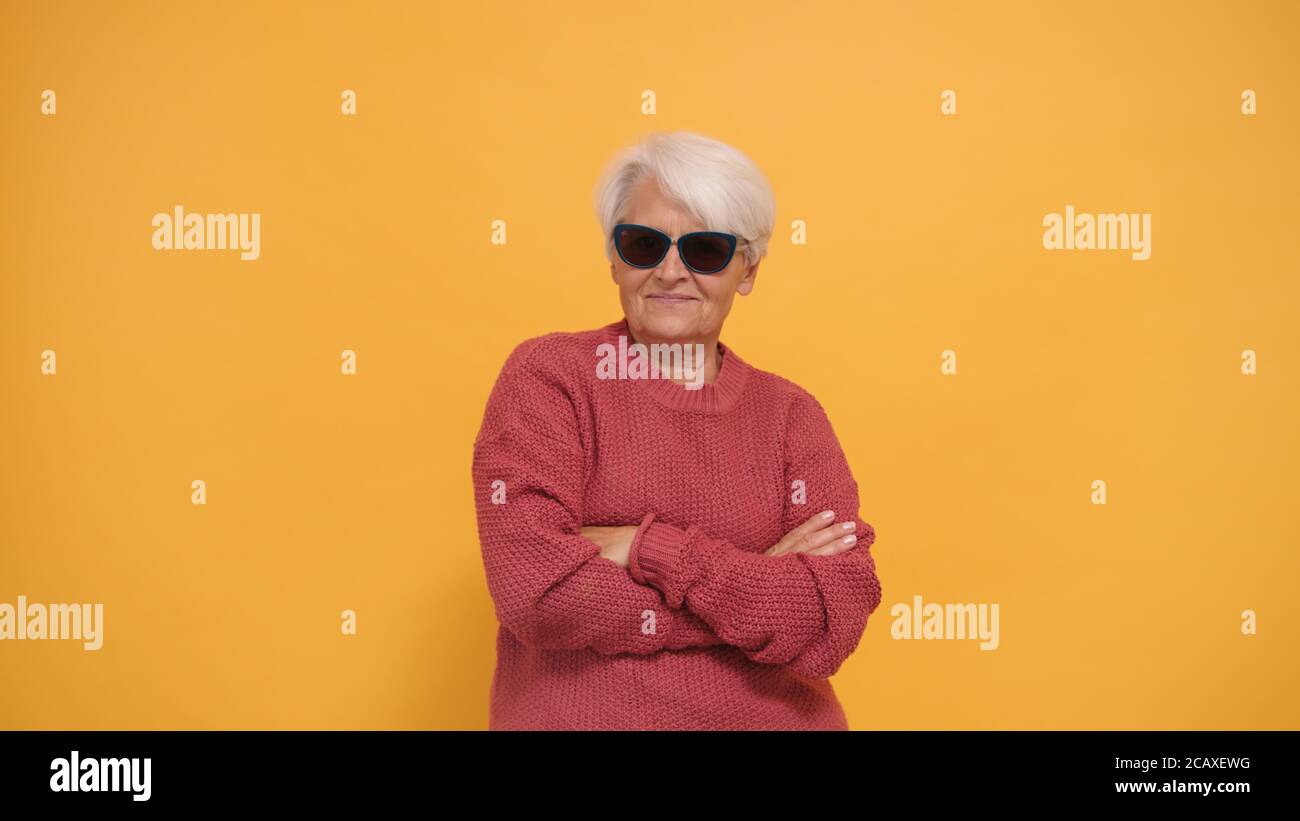 Donna anziana fresca con capelli corti e occhiali da sole grigi e mani incrociate. Isolato. Foto di alta qualità Foto Stock