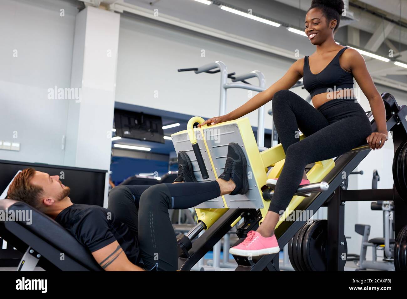 il formatore traccia la correttezza dell'esercizio in palestra, insegna alle persone a svolgere esercizi con pesi Foto Stock il formatore traccia la correttezza dell'esercizio in palestra, insegna alle persone a svolgere esercizi con pesi Foto Stock