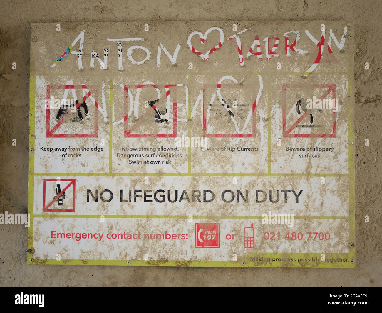 I nomi di Anton e Tarryn e un cuore scritto su un cartello di emergenza polveroso presso la spiaggia durante il periodo di blocco 2020 Covid-19, Città del Capo. Foto Stock