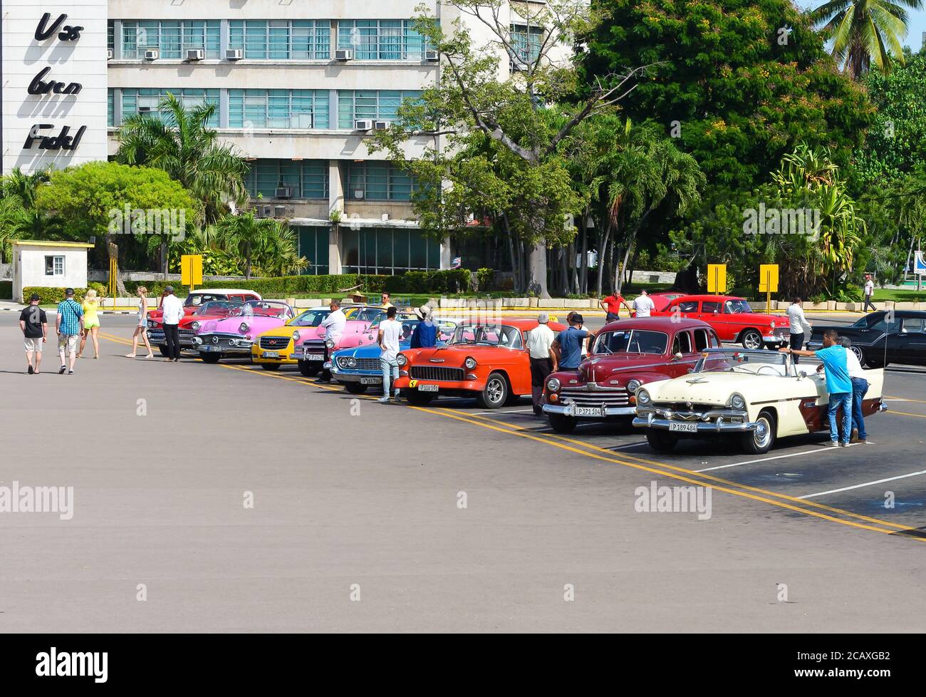 Gamma di auto classiche e colorate a Revolution Square. Cubano guida in attesa di turisti a guidare i veicoli d'epoca a l'Avana, Cuba. Foto Stock