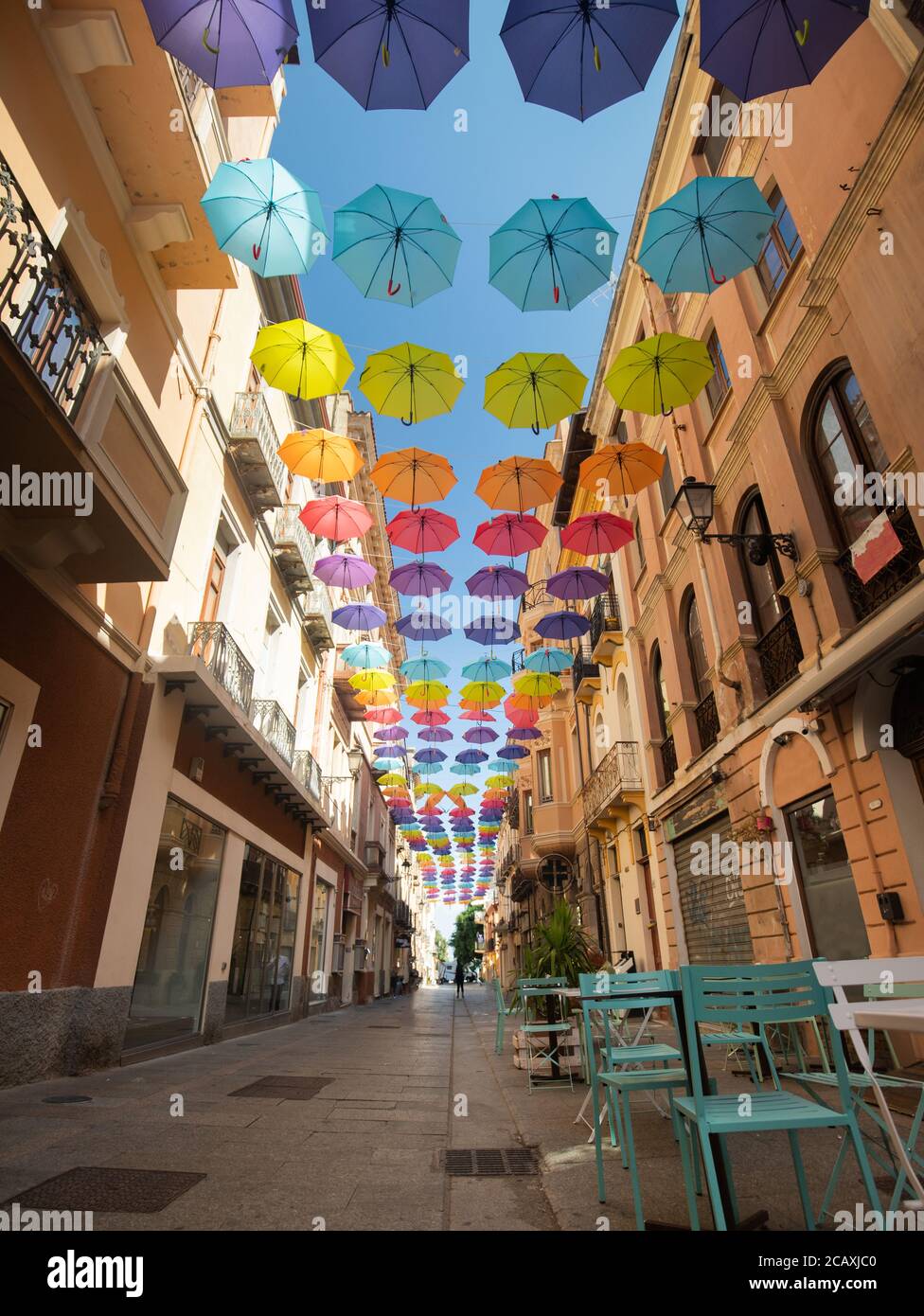 Glesias, Italia: Ombrelli colorati appesi su una strada nella vecchia città  di Iglesias in una giornata di sole Foto stock - Alamy