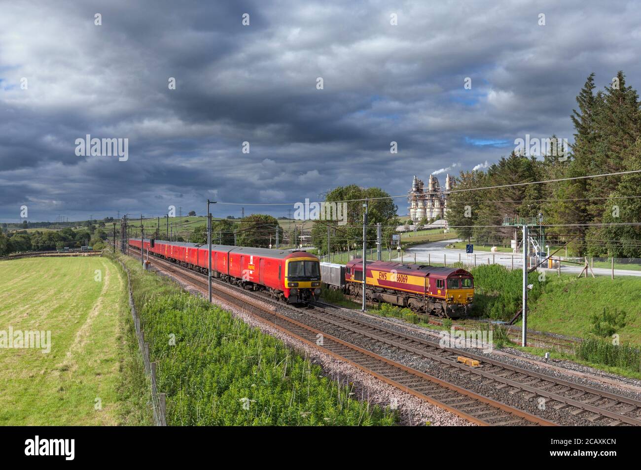 Classe di posta reale 325 che passa una classe di carico DB 66 Locomotiva con un treno merci a Hardendale calce opere su La linea principale della costa occidentale di Cumbria Foto Stock