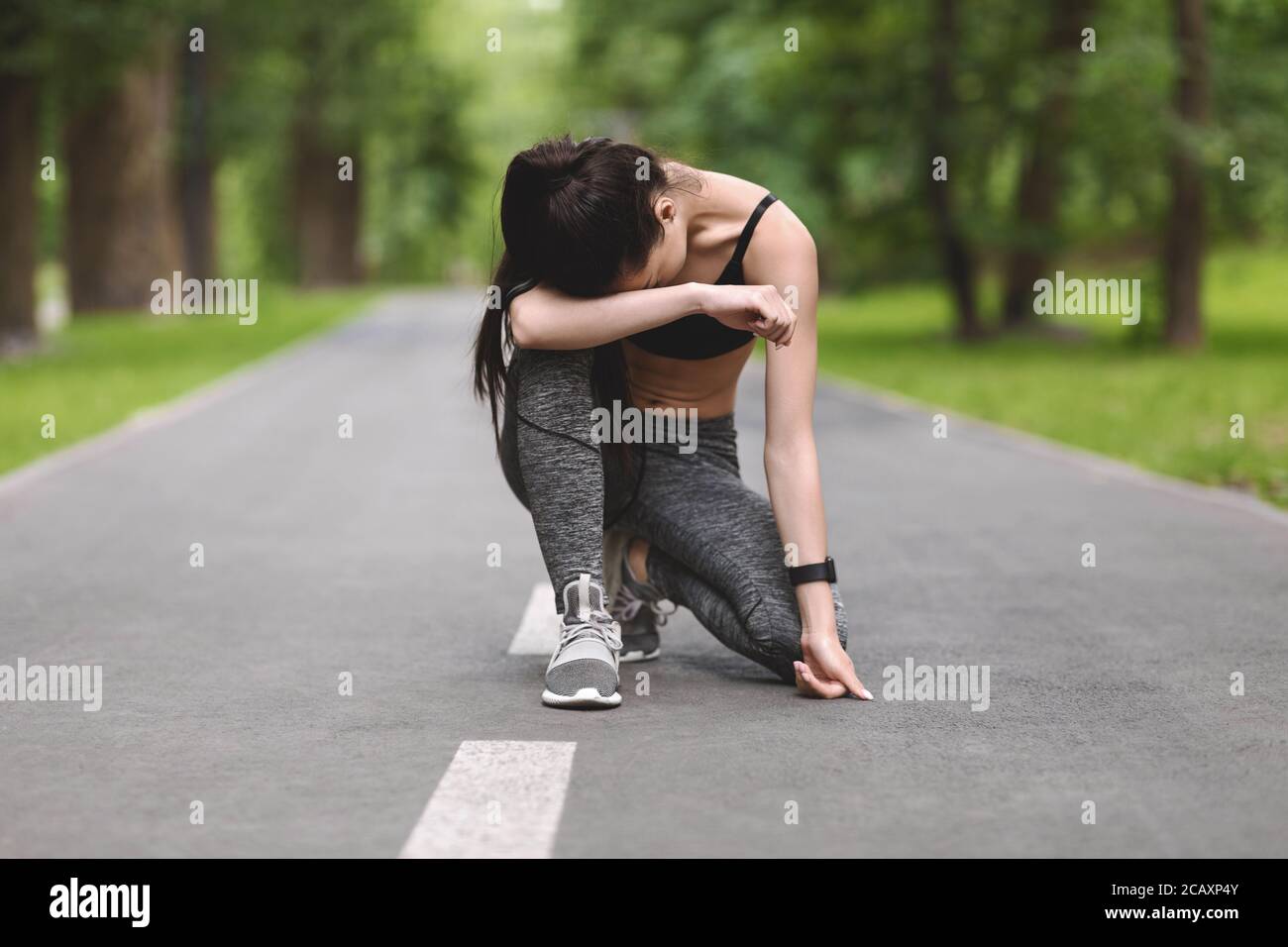 Esausta ragazza Jogger Asiatica riposante su Path in Park After Corsa lunga Foto Stock