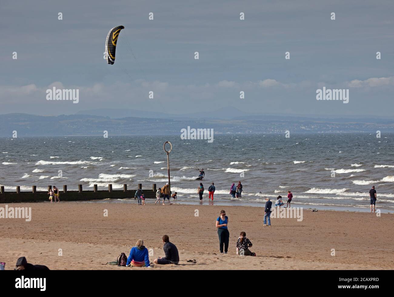 Portobello, Edimburgo, Scozia, Regno Unito. 9 agosto 2020. Kite Surfer in background con la spiaggia groyes.More persone sulla spiaggia nel tardo pomeriggio, il vento fresco che dà la rara opportunità di Kite Surf sul Firth of Forth a Porty. Foto Stock