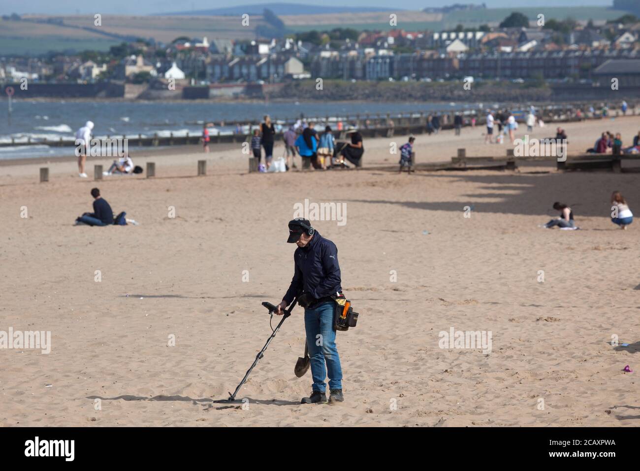 Portobello, Edimburgo, Scozia, Regno Unito. 9 agosto 2020. Più persone sulla spiaggia nel tardo pomeriggio e un detctor di metallo. Foto Stock