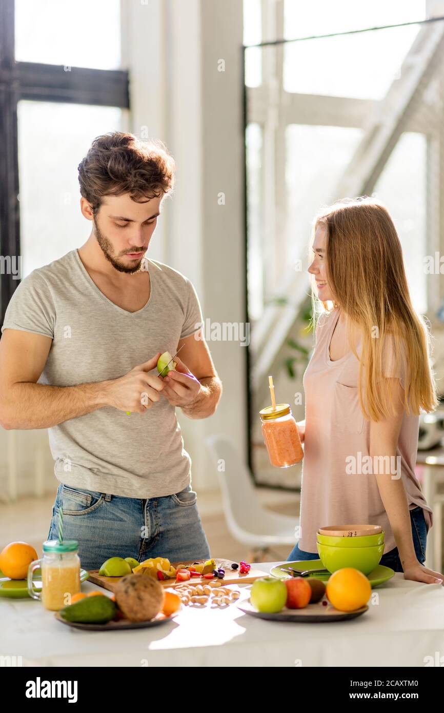 il ragazzo attraente sta arando la mela con agirl nella cucina moderna Foto Stock