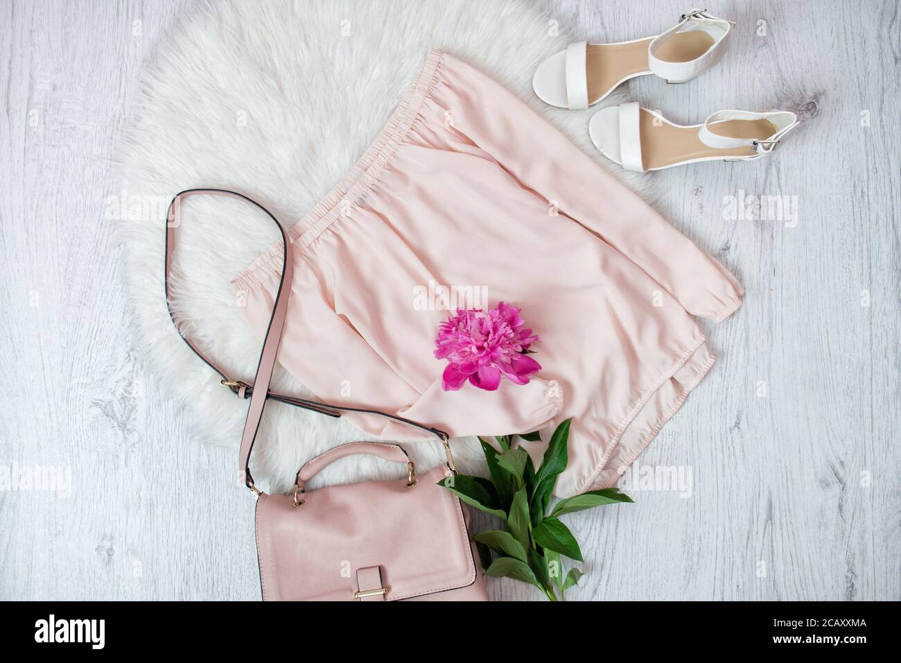 Blusa rosa, borsa, scarpe e una peonie. Concetto alla moda, pelliccia bianca sullo sfondo Foto Stock