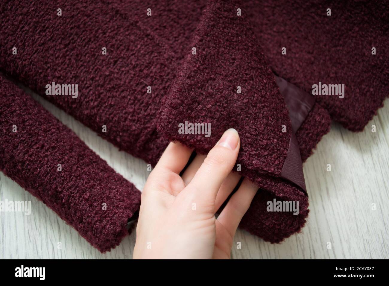Cappotto di Borgogna in mano femminile. Concetto alla moda. Primo piano Foto Stock